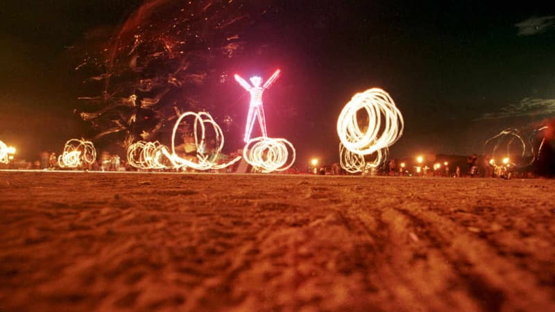 Des danseurs et l'effigie de néon du festival Burning Man, en 1998.