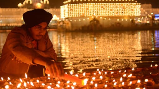Devant le Temple d'or d'Amritsar, en Inde, un dévôt sikh célèbre la fête des lumières en allumant les bougies.