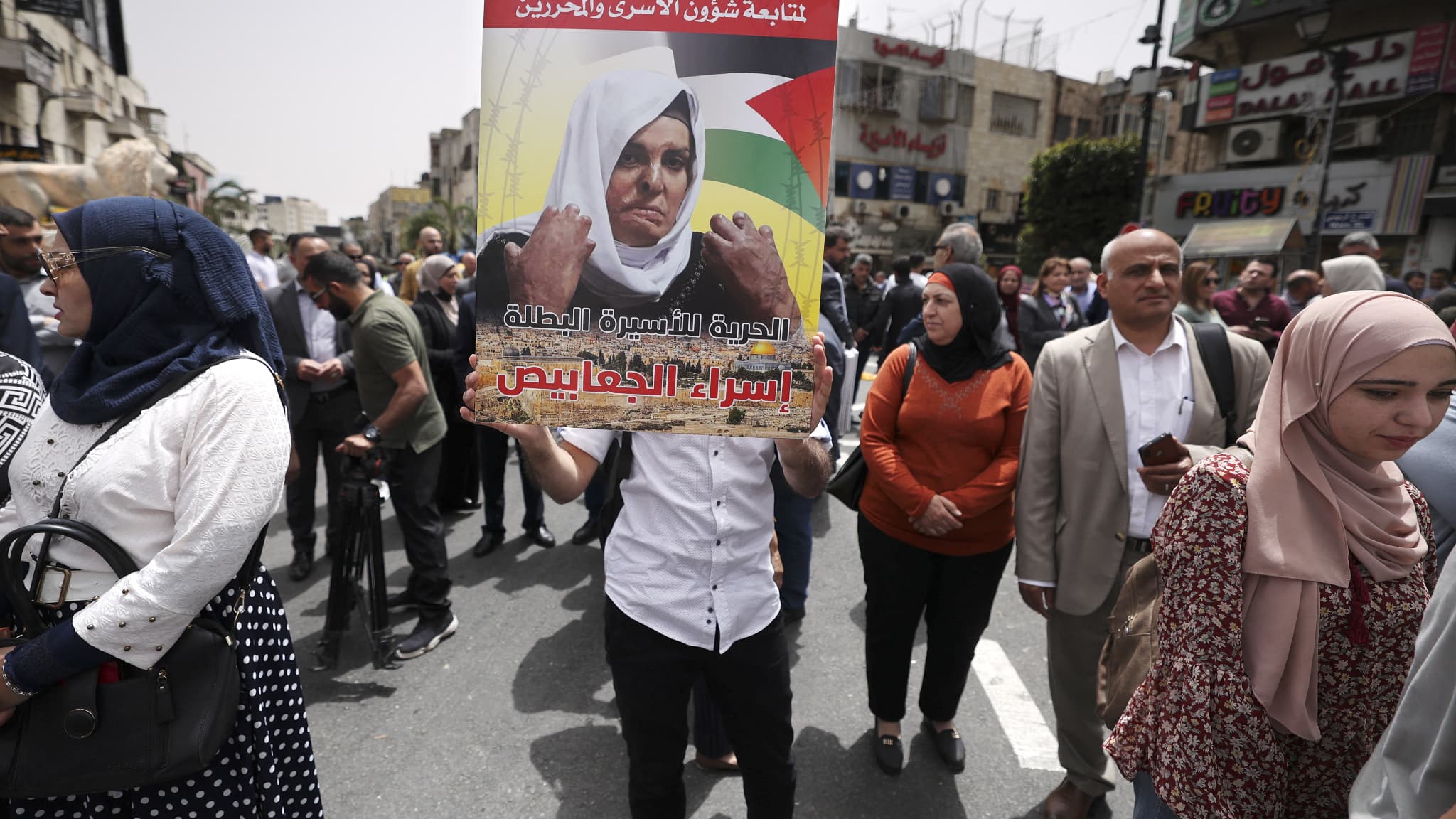 Une photo de la Palestinienne Israa Jaabis, détenue dans une prison israélienne après avoir blessé un policier en faisant exploser une bombonne de gaz en 2015, brandie sur une pancarte par une manifestante à l'occasion de la journée pour les prisonniers palestiniens pour demander leur libération, à Ramallah, le 17 avril 2022