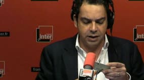 Le journaliste Patrick Cohen découpant en direct, mardi matin, sa carte de presse.