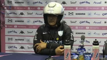 Laurent Travers, coach du Racing, se pointe avec un casque sur la tête en conférence de presse d'après le derby, 26 mars 2023