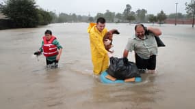 Des habitants de Houston se fraient un chemin dans leur quartier inondé, le 28 août 2017 à Houston (Texas). 