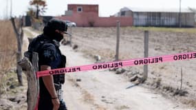 Un policier garde l'entrée du ranch Izaguirre dans la communauté de La Estanzuela où le collectif « Guerreros Buscadores » a localisé trois fours crématoires humains lors de la recherche de leurs proches à Teuchitlan, dans l'État de Jalisco (Mexique), le 10 mars 2025.