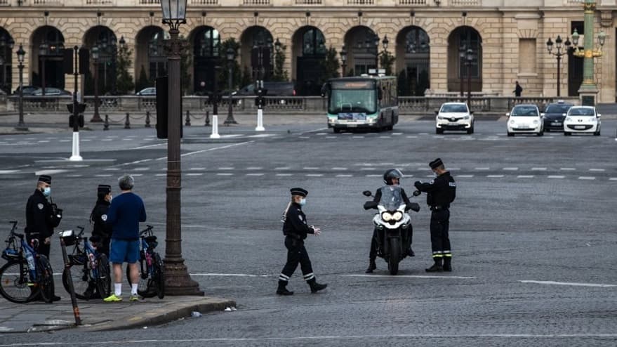 Des forces de l'ordre en train de contrôler un individu en scooter à Paris au premier jour du confinement au moins de mars 2020