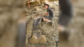 Maxime Lasseron, le premier paléontologue à être tombé sur le fossile, pose à côté du fémur de sauropode. 