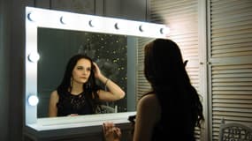 Une jeune femme se regarde dans un miroir. 