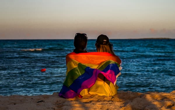 Deux femmes assises le long de la plage avec un drapeau LGBT sur les épaules, dans un hôtel de Guillermo Key (Cuba), le 27 novembre 2021.