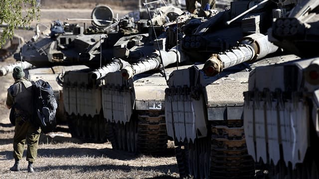Un soldat israélien marche le long des tanks Merkava alignés sur la frontière.
