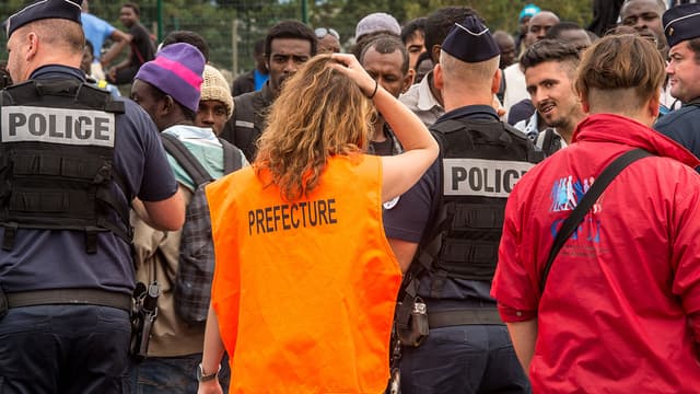 Une responsable de la préfecture du Pas-de-Calais dirigent des migrants vers un bus qui doit les emmener dans un Centre d'accueil et d'orientation (CAO). 9.000 migrants de la jungle de Calais vont être répartis sur tout le territoire sur ordre des préfectures.