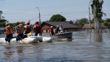Des habitants de Kherson, en Ukraine, sur des bateaux après la destruction partielle du barrage de Kakhovka la veille qui a entraîné l'inondation de la ville, le 7 juin 2023