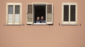 Des Italiens en train d'assister à une messe depuis leur fenêtre à Rome, en raison des mesures de confinement liées au coronavirus.