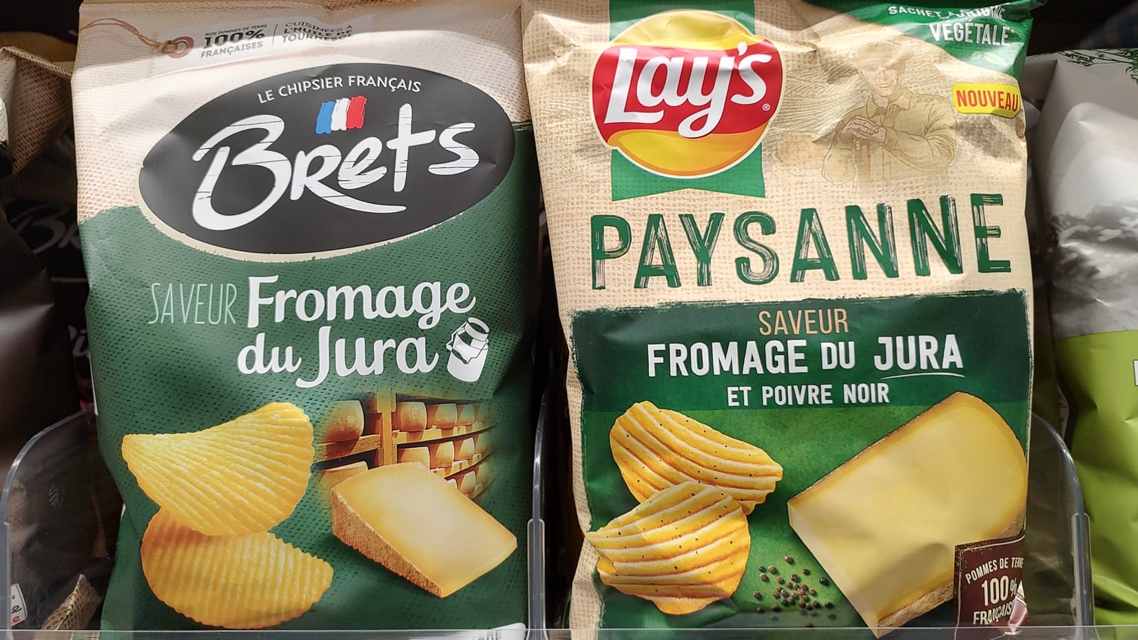Un paquet de chips au "fromage du Jura" de la marque Brets et un paquet de chips au "fromage du Jura et poivre noir" de la marque Lays. Un paquet de chips au "fromage du Jura" de la marque Brets et un paquet de chips au "fromage du Jura et poivre noir" de la marque Lays.
