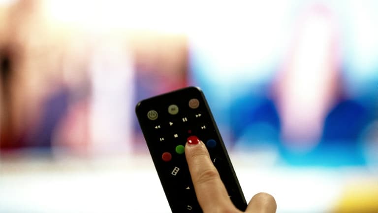 Une personne tient une télécommande pointée vers un écran de télévision, à Paris le 15 janvier 2025