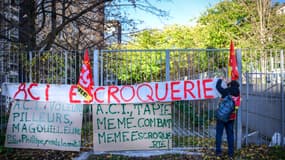 Un employé du groupe ACI accroche une banderole sur une clôture avec les mots "ACI, fraude" lors d'un rassemblement devant le tribunal de commerce à Lyon, dans le centre-est de la France, le 9 décembre 2025, à l'occasion d'une audience concernant les dettes du groupe industriel.