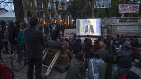 Des jeunes, participant au mouvement Nuit debout, regardent l'intervention télévisée du chef de l'Etat, place de la République à Paris le 14 avril 2016.