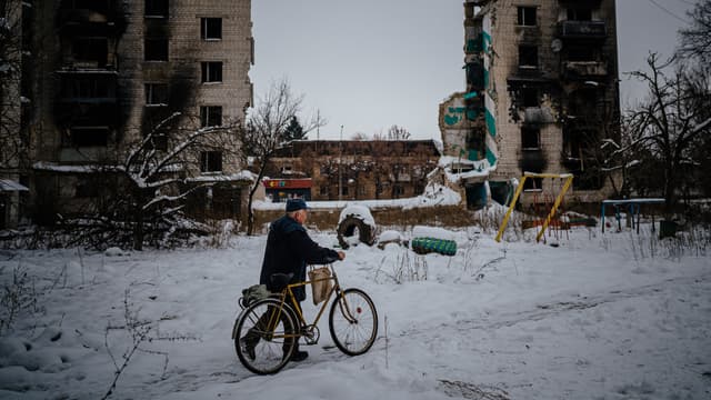 Un habitant pousse son vélo dans une rue enneigée à côté de bâtiments résidentiels détruits à Borodyanka, près de Kiev, le 4 décembre 2022. (illustration)