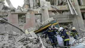 Des pompiers transportent le corps d'une victime après une frappe russe sur un bâtiment de l'administration régionale de Mykolaïv, le 29 mars 2022 en Ukraine