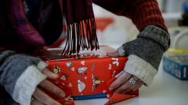 Image d'illustration - Dans un magasin de jouets à Paris, le 16 décembre 2019, une salariée en train d'emballer un cadeau de Noël.