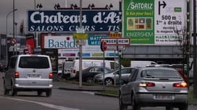 Des voitures passent devant des enseignes publicitaires à Wittenheim, dans le Haut-Rhin, le 12 décembre 2023