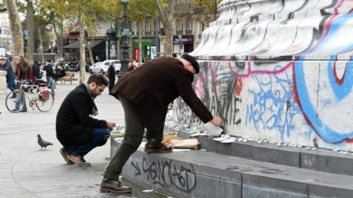 Des personnes posent des fleurs et des bougies face au monument de la Place de la République, le 14 novembre 2015 à Paris