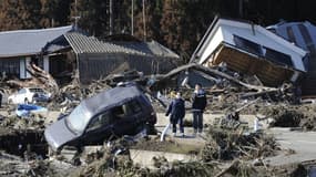 Des piétons se tiennent à côté de maisons effondrées après avoir été frappés par un tsunami à Minamisoma, préfecture de Fukushima, le 12 mars 2011. (Photo d'illustration)