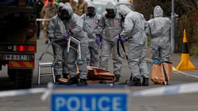 Des militaires britanniques en tenue protectrice déplacent un véhicule lié à l'empoisonnement d'un ex-espion russe, le 14 mars 2018 à Salisbury en Grande-Bretagne. 