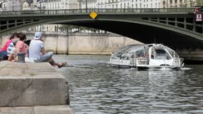 Les touristes regardent un bateau-mouche sur la Seine, à Paris, le 9 juin 2014.