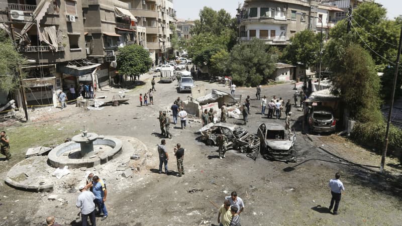 Des Syriens se rassemblement pour inspecter les dégâts causés par un attentat-suicide sur la place Tahrir, à Damas le 2 juillet 2017.
