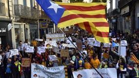 Des manifestants brandissent des drapeaux catalans et tiennent des bannières de l'association catalane La Bressola lors d'un rassemblement contre le projet de la mairie d'acquérir le Couvent Sainte-Claire à Perpignan, dans le sud de la France, le 23 octobre 2021. 