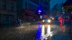 Des personnes courent s'abriter dans une rue du 20e arrondissement pendant un orage, à Paris, le 25 juin 2025.