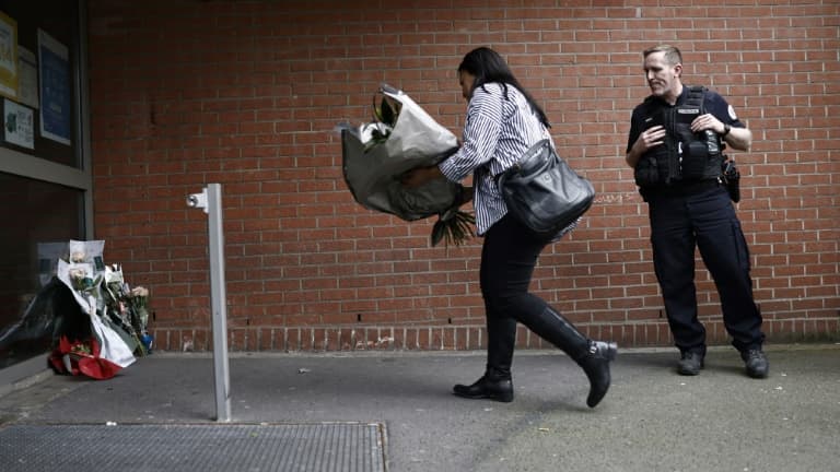 Une femme dépose un bouquet de fleurs devant le commissariat de police de Roubaix (Nord) en homme aux policiers tués dans un accident de la route, le 21 mai 2023