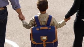 Un enfant tenant la main à des adultes (photo d'illustration)