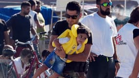 Un garde-côte grec s'occupe d'un enfant migrant intercepté entre la Turquie et la Grèce, dans le port de Kos, le 18 août 2015.