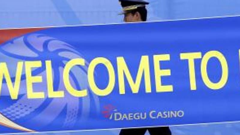 Un officier de police coréen passe devant une banderole de bienvenue au village des athlètes à Daegu