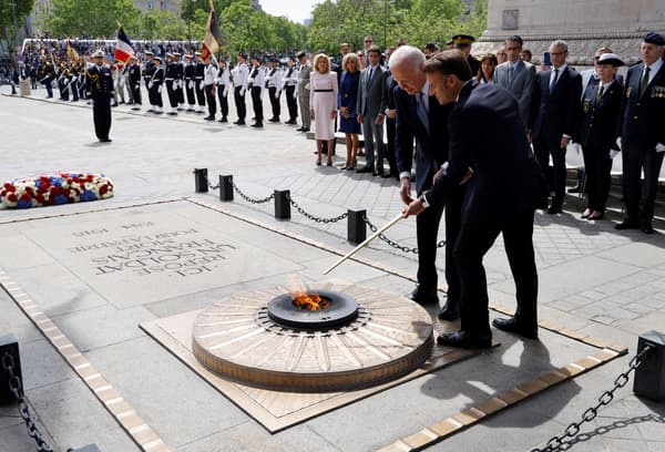 Le président français Emmanuel Macron et le président américain Joe Biden ravivent la flamme de la Tombe du Soldat inconnu lors d'une cérémonie à l'Arc de Triomphe à Paris, le 8 juin 2024.