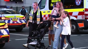 Une femme et trois enfants accompagnés par des secours après une attaque au couteau à Sydney, en Australie, le 13 avril 2024