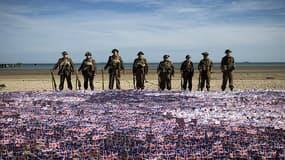 Sur Gold Beach, à Asnelles, des hommes en uniforme britannique d'époque posent devant une mer de petits drapeaux du Royaume-Uni.