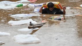 Un homme porte un sac de farine au Katmandu inondé, le 8 septembre 2024