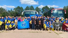  Sur cette photo prise et publiée par le quartier général de coordination pour le traitement des prisonniers de guerre le 14 août 2025, des prisonniers de guerre ukrainiens, enveloppés dans des drapeaux nationaux ukrainiens, posent pour une photo après un échange dans un lieu tenu secret.