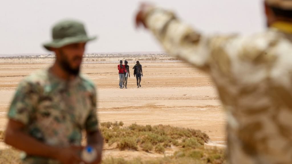 Des gardes-frontières libyens et des migrants, près d'Al-Assah, à la frontière entre la Libye et la Tunisie, le 30 juillet 2023.