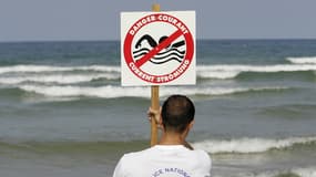 Un CRS maître-nageur-sauveteur installe un panneau indiquant la présence de courants de baïne, le 21 juillet 2004 sur la plage de Lacanau. Les baïnes, courants dangereux qui entraînent les nageurs au large en quelques secondes, sont le principal souci des maîtres-nageurs-sauveteur (MNS) du littoral aquitain.