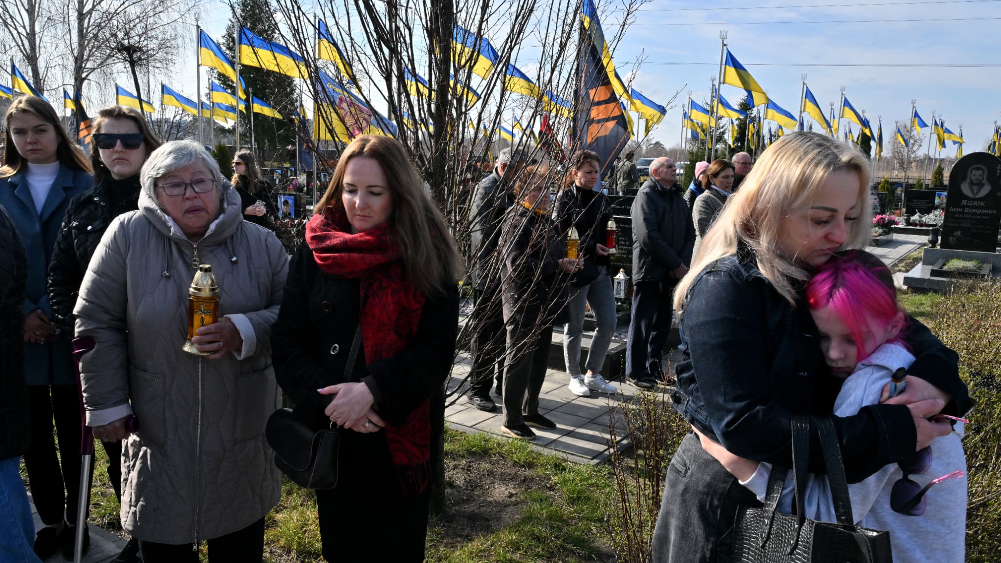 Des personnes en deuil participent à une cérémonie commémorative dans l'allée des héros du cimetière de la ville de Boutcha, le 30 mars 2025, à l'occasion du troisième anniversaire de la libération de la ville ukrainienne du contrôle russe, le 31 mars 2022.