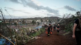 Cette photo prise et diffusée par la Sécurité civile française le 17 décembre 2024 montre des membres de la Sécurité civile marchant avec des tronçonneuses à un endroit non divulgué sur le territoire français de Mayotte dans l'océan Indien, à la suite du cyclone Chido.