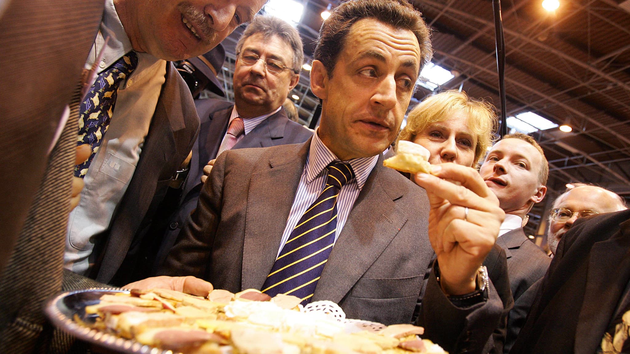 Nicolas Sarkozy, alors ministre de l'Intérieur, goûte du fromage lors du Salon de l'agriculture, le 2 mars 2006.