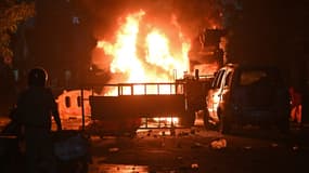 Un pompier se tient près des véhicules incendiés à la suite d'affrontements dans le quartier de Chitnavis Park Square, à Nagpur (Inde), le 17 mars 2025.