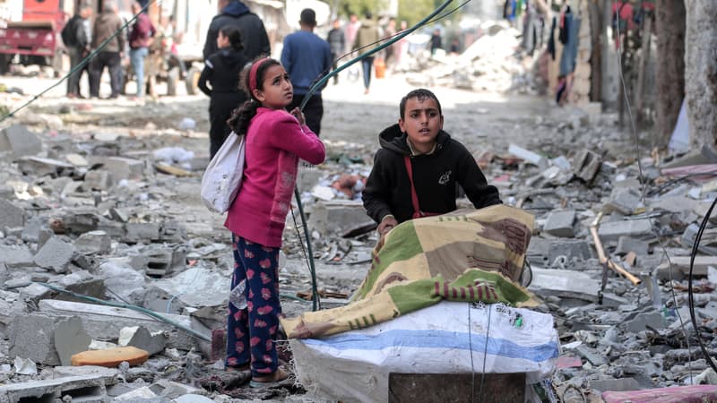 Des enfants palestiniens récupèrent certains objets trouvés au milieu des destructions causées par les bombardements israéliens à Bureij, dans le centre de la bande de Gaza, le 14 mars 2024, alors que la guerre entre Israël et le mouvement Hamas se poursuit.