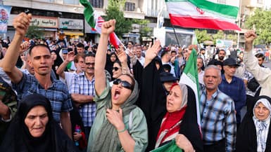 Des Iraniens brandissent des drapeaux et des pancartes lors d'un rassemblement de protestation contre l'attaque américaine contre l'Iran sur la place Enghelab à Téhéran, le 22 juin 2025. 