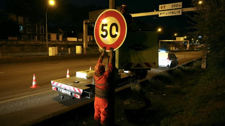 Un ouvrier installe un panneau de limitation à 50 km/h sur le périphérique au niveau de la porte d'Ivry, à Paris, le 30 septembre 2024