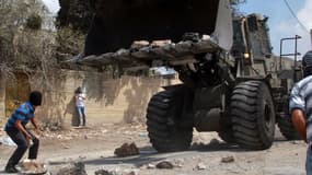 Un Palestinien jette une pierre contre un bulldozer israélien le 20 septembre 2013, à Kfar Qaddum.