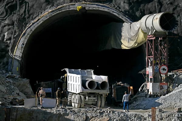 Le personnel de sécurité observe un camion transportant des tubes métalliques à travers l'entrée du tunnel routier en construction de Silkyara, quelques jours après son effondrement dans le district d'Uttarkashi de l'État indien de l'Uttarakhand, le 21 novembre 2023.